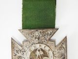 an old silver medal with a green ribbon on a white background