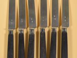 six couteaux sont alignés sur une surface jaune
