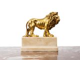 a gold statue of a lion standing on a marble base
