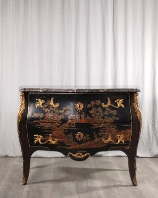 une photo d'une commode noire et dorée posée sur un parquet