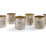 six coupes en argent ornées de motifs, posées sur une surface blanche