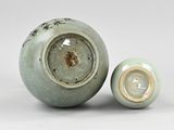 a small green vase and a smaller one sitting next to each other