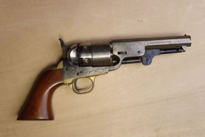 un vieux revolver à crosse en bois posé sur une surface en bois