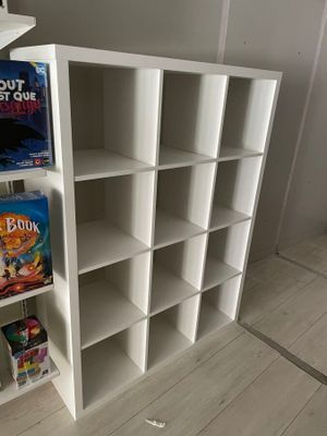 une bibliothèque blanche sur laquelle sont posés de nombreux livres