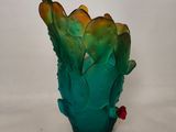 a green vase with a red flower in it on a table