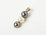 a close up of a pearl and diamond pendant on a white surface