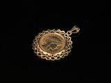 a gold pendant with a coin in it on a black background