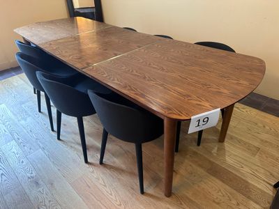 une table en bois avec des chaises noires et un miroir accroché au mur