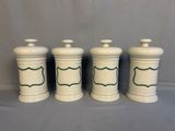 three white ceramic jars with green trims on them on a gray surface