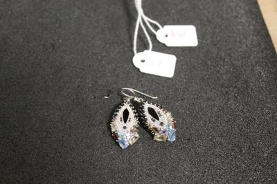 une paire de boucles d'oreilles posée sur une table, à côté d'une étiquette de prix