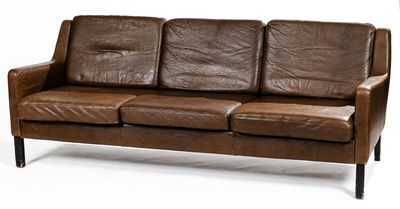 brown leather sofa with black legs and arm rests on a white surface