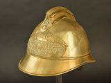brass fire helmet on a stand against a black background