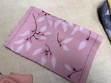 a pink pouch with a pattern on it next to a pair of scissors and a pair of cloths