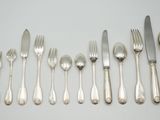 un ensemble d'argenterie, comprenant notamment des fourchettes et des cuillères, posé sur une table