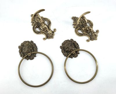 three antique brass towel rings with lion heads on them