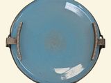 a blue plate with a metal handle on a white background
