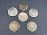 six different types of silver coins on a black surface