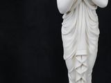a white statue of a woman standing on a black background