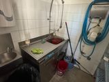 a kitchen with a sink and a trash can in it