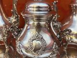 une théière en argent posée sur une table à côté d'autres théières en argent