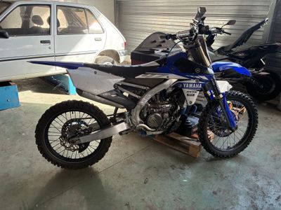 une moto tout-terrain garée dans un garage à côté d'une voiture