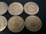 six different british coins sitting on top of a black surface
