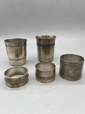 four silver cups and a napkin holder on a white surface