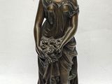 une statue en bronze représentant une femme tenant un panier de fleurs
