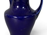 pichet en verre violet avec une anse incurvée sur fond blanc