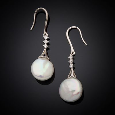 une paire de boucles d'oreilles en perles et diamants sur fond noir