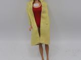 poupée Barbie portant un manteau jaune et une robe rouge, aux cheveux noirs