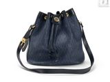 un petit sac seau bleu avec une boucle dorée sur la poignée