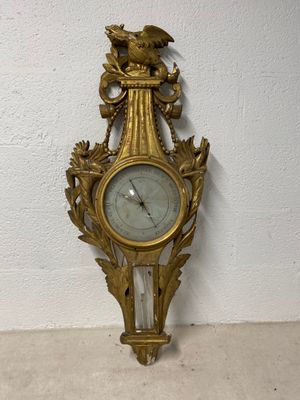 a gold clock on the wall with a bird on it