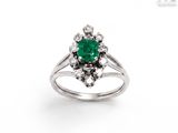 gros plan d'une bague avec une pierre verte entourée de diamants
