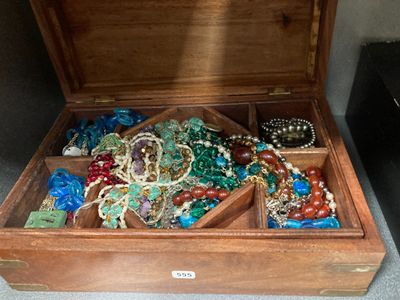 une boîte en bois remplie de nombreux bijoux, posée par terre