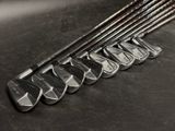 Plusieurs clubs de golf sont alignés sur une surface noire