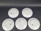 four white plates with black dots on them sitting on a table