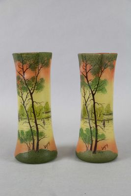 pair of vases with trees painted on them sitting on a table