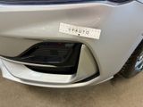 the front bumper of a silver car with a sticker on it