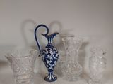 un vase bleu et blanc posé sur une table, à côté d'autres objets en verre