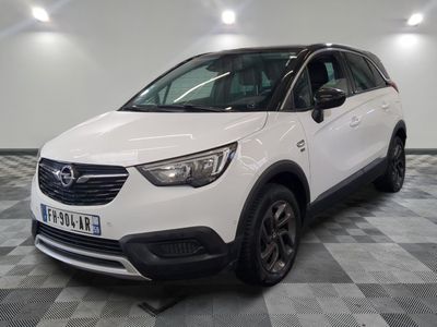 L'Opel blanche est garée dans une grande pièce au sol carrelé en damier.