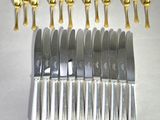 six knives and six spoons are lined up on a table