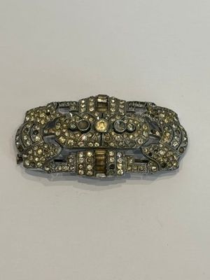 un gros plan d'une broche en argent et en or posée sur une surface blanche