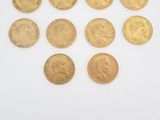 six gold sovereigns of various sizes and shapes on a white surface
