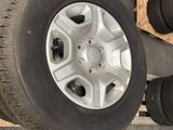 four tires on a pallet next to a pile of other tires