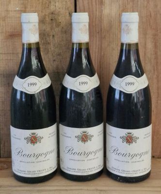 three bottles of wine sit on a shelf in front of a wooden wall