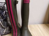 pair of green and pink rain boots sitting on top of a wooden table
