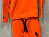 un gros plan sur le sweat à capuche et le pantalon orange d'un enfant