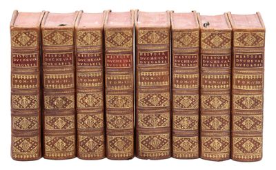 six vieux livres sont alignés sur une surface blanche