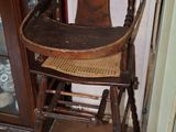 une chaise haute en bois avec une assise en osier, placée devant un meuble